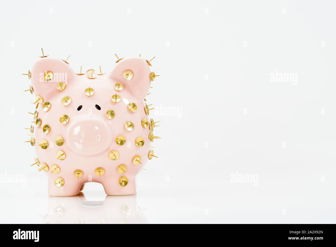 Image conceptuelle illustrant la protection des économies et des investissements montrant une banque de porc rose protégée par des piles de dessin et isolée contre le blanc. Banque D'Images