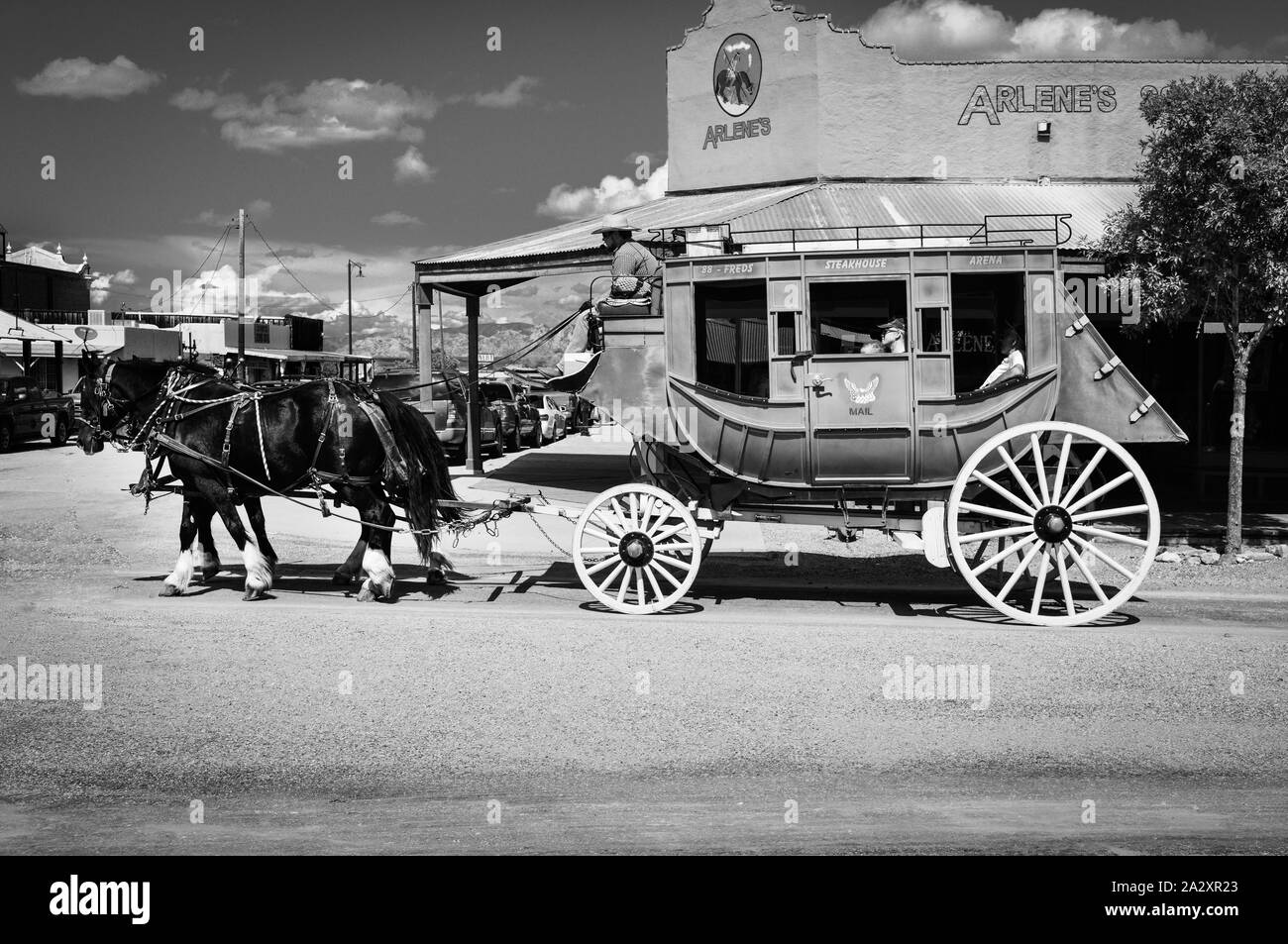 Un ancien relais de diligences tirées par deux chevaux guidée par le pilote avec les touristes à bord de cow-boy à Tombstone, en Arizona, USA, en noir et blanc Banque D'Images