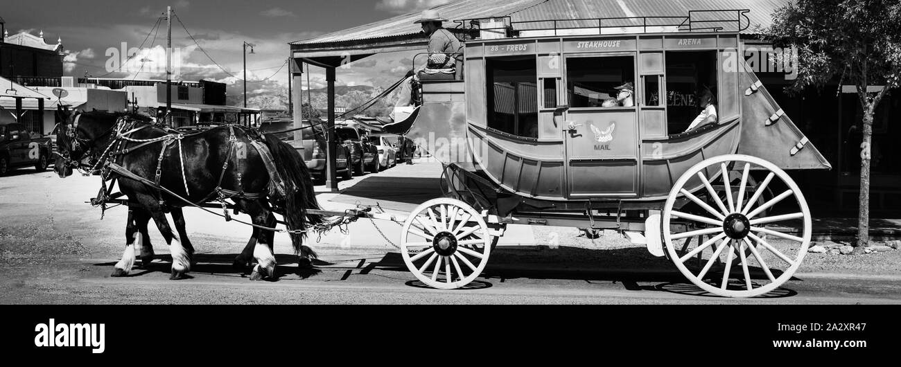 Un format panoramique d'un antique stagecoach tiré par deux chevaux guidée par le pilote avec les touristes à bord de cow-boy à Tombstone, en Arizona, USA, en B & W Banque D'Images