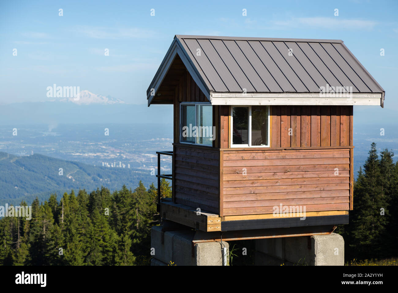 Une cabane en bois au sommet de Seymour Mountain en été avec vue sur le mont Baker au loin. Banque D'Images