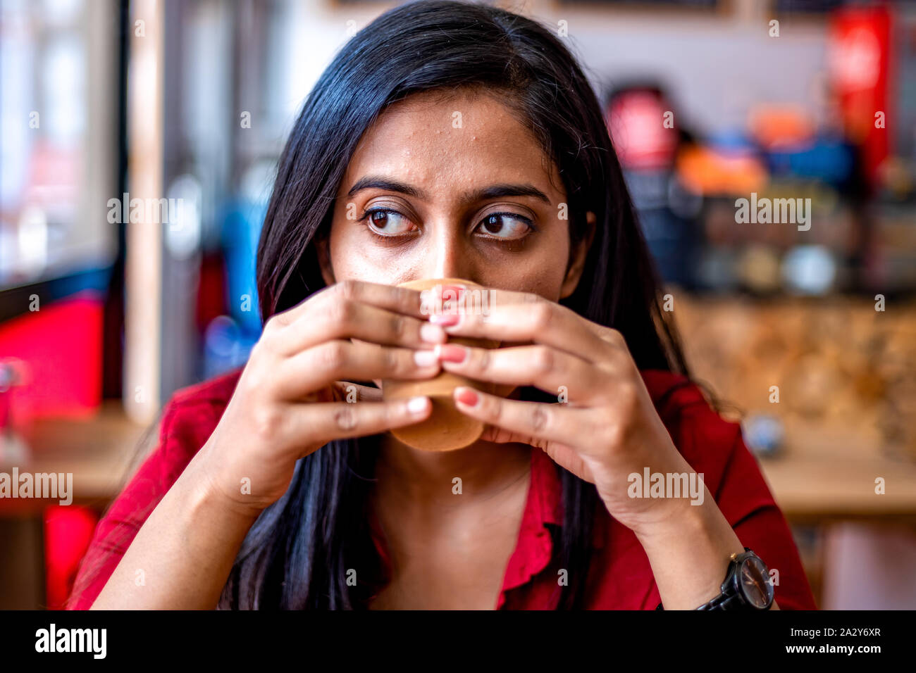 Belle jeune fille avec une tasse de café ou de thé dans un pot en argile dans un restaurant boisson chaude. Banque D'Images