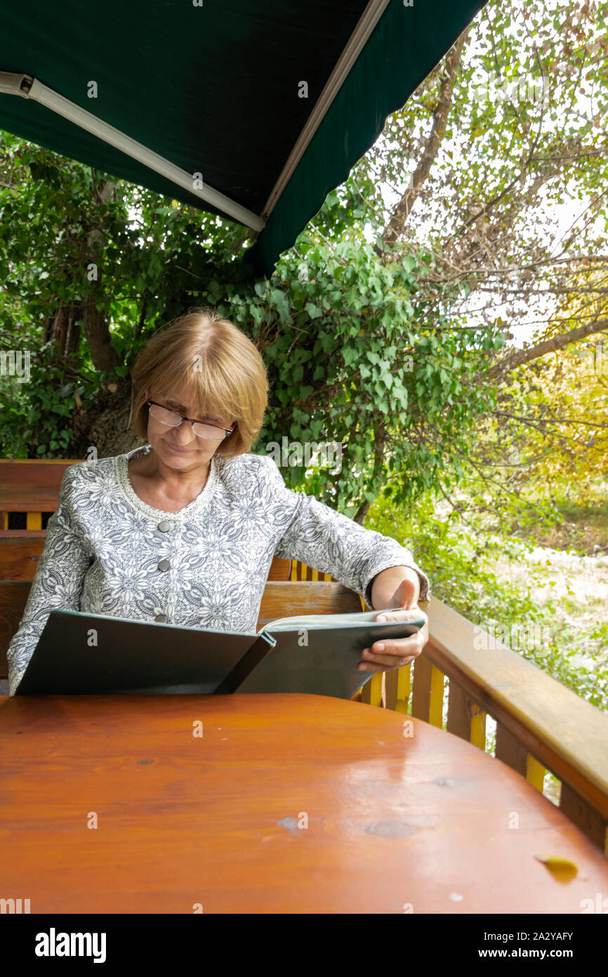 Attractive senior à la recherche d'un menu dans le restaurant en plein air. Concept de vie sain et actif Banque D'Images