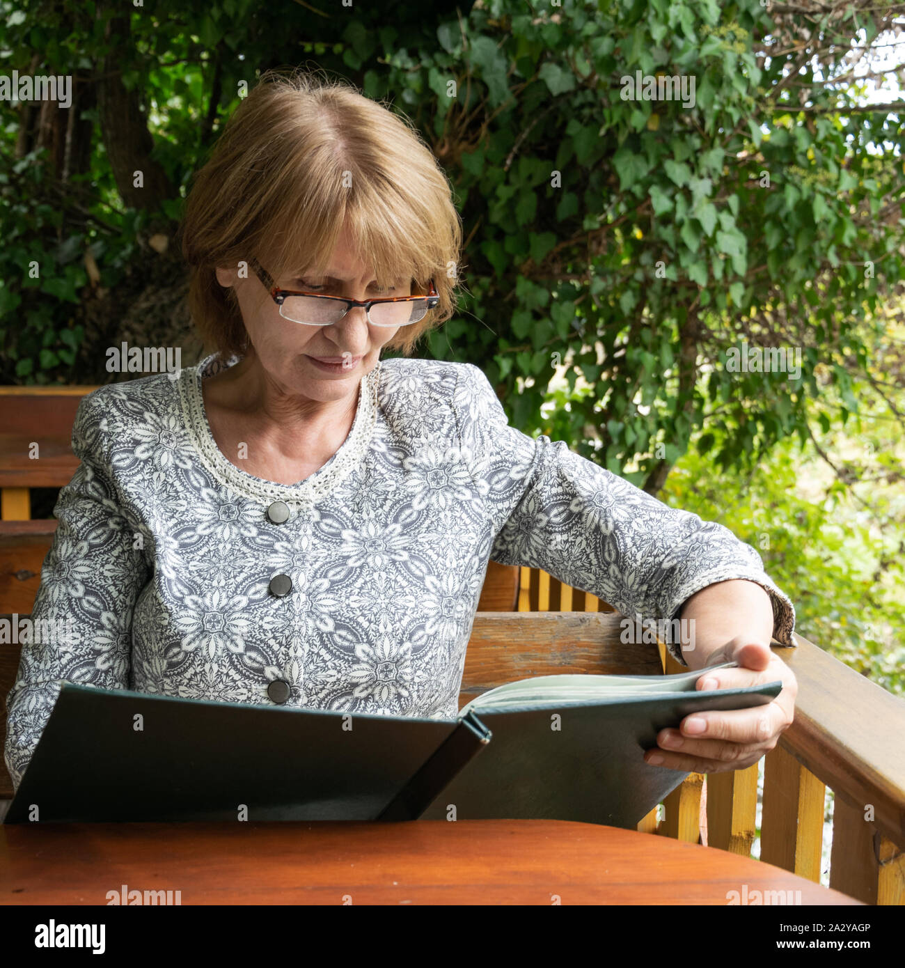 Attractive senior à la recherche d'un menu dans le restaurant en plein air. Concept de vie sain et actif Banque D'Images