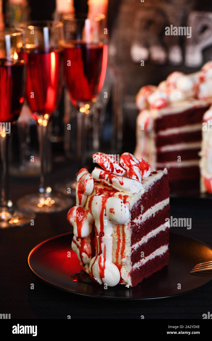 Un morceau de gâteau creepy (velours rouge), décorée avec des os de meringue et couvert de sang. Excellente idée que de traiter les clients. Close-up. Banque D'Images