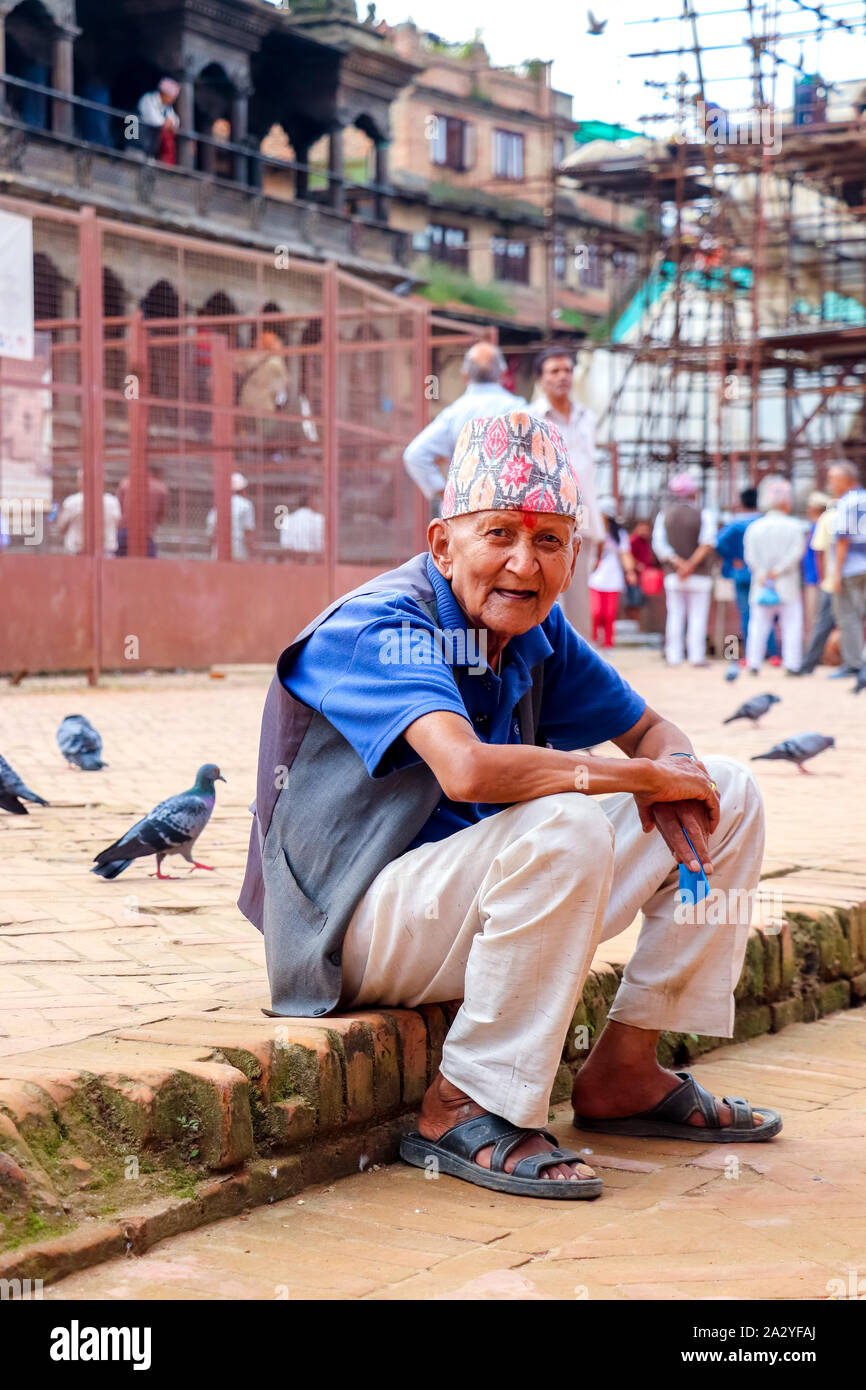 Un vieil homme népalais avec visage heureux regardant la caméra assis à Patand Durbar Square Banque D'Images