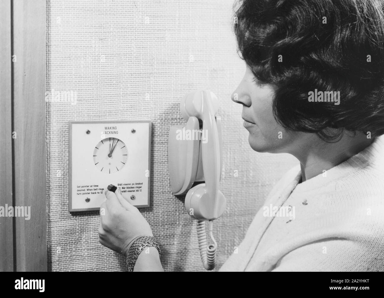 Un client de l'hôtel est saisie de l'heure lorsqu'elle veut l'alarme se déclenche sur son réveil. Années 1950 Banque D'Images