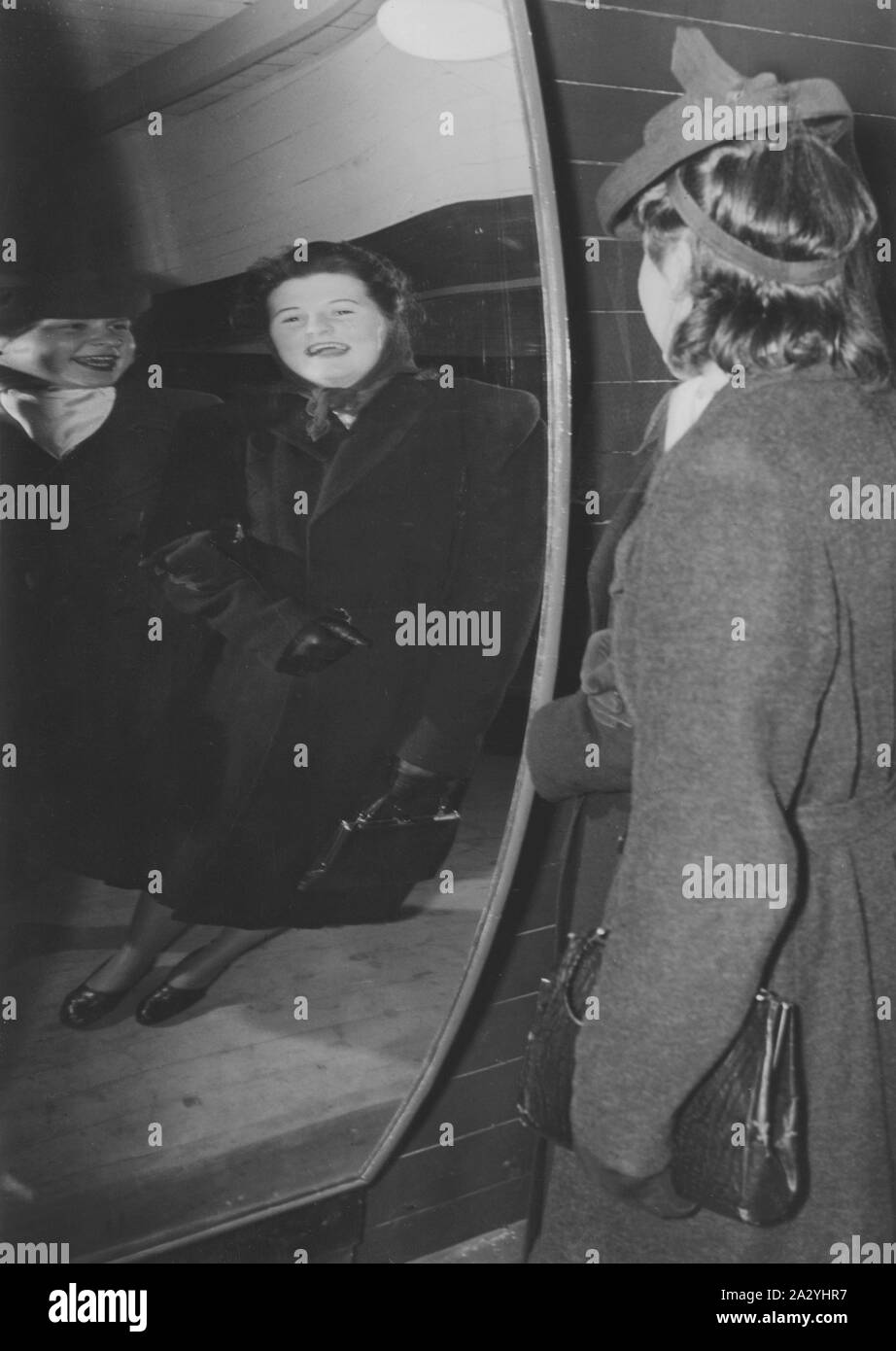 Parc de loisirs dans les années 40. Deux femmes rient de leur apparence dans un drôle de miroir. Miroirs de formes différentes rend la réflexion de personnes plus grandes et minces, ou courts et gras. Stockholm Gröna Lund Suède 1940 Banque D'Images