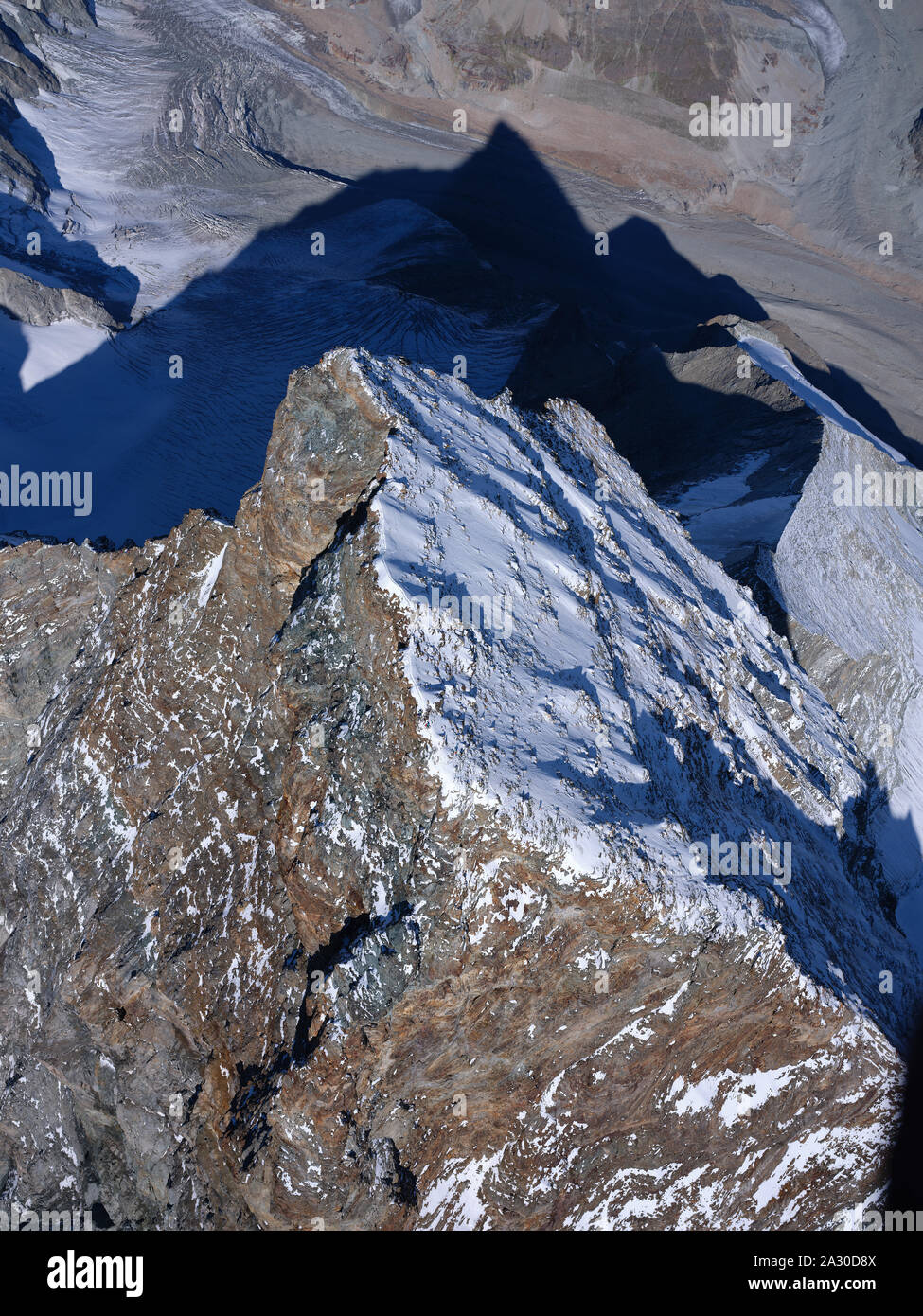 VUE AÉRIENNE. Sommet de Matterhorn / Cervino de 4478 mètres de haut. Longue crête séparant l'Italie de Breuil-Cervinia (côté rocailleux) de la Suisse à Zermatt. Banque D'Images