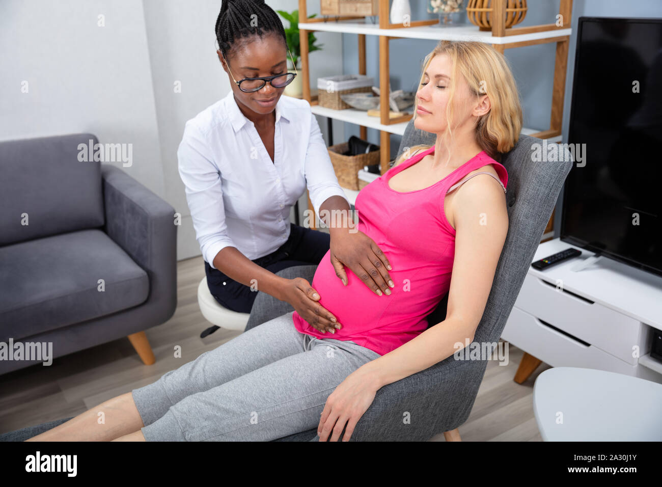 La femme enceinte ayant un massage relaxant du thérapeute à la maison de l'Afrique Banque D'Images