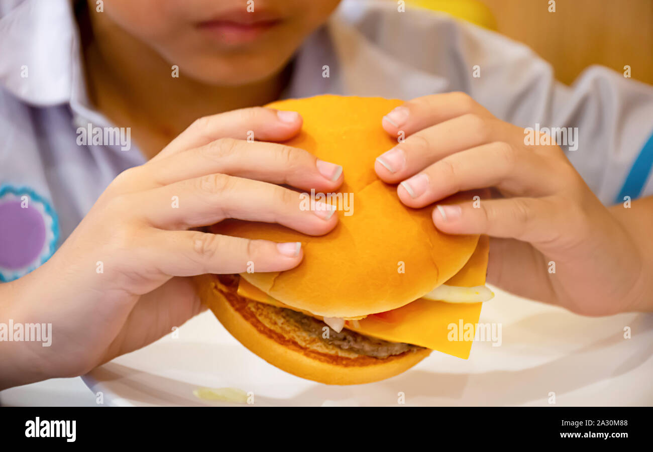 Le poisson et le fromage à hamburger dans la main asie boy holding l'alimentation. Banque D'Images