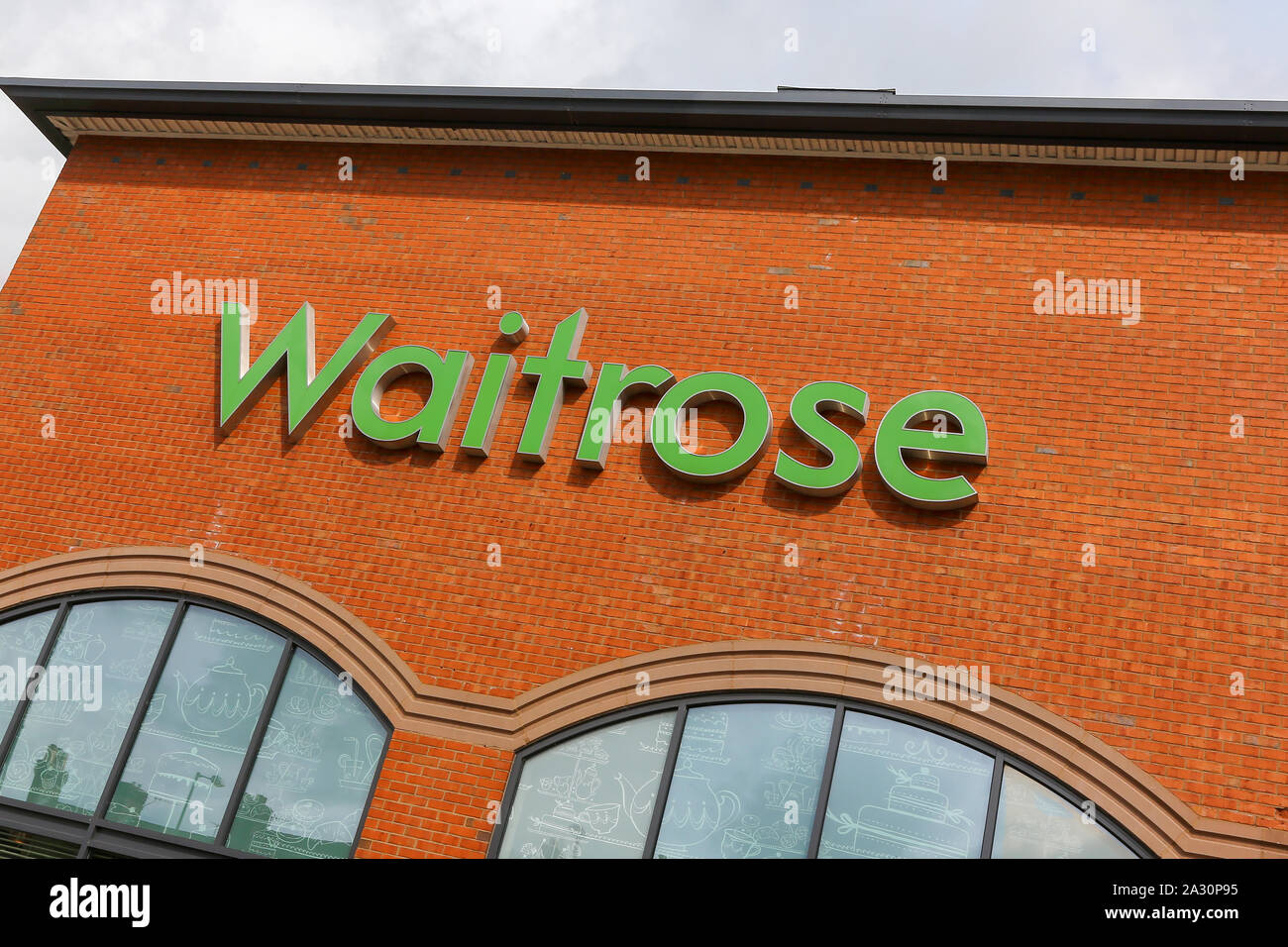 Un signe pour un supermarché Waitrose en lettres vertes sur un mur de brique rouge Banque D'Images