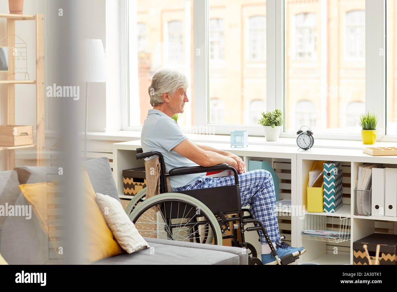 Senior patient assis en fauteuil roulant et en regardant par la fenêtre lors de la récupération après la maladie à la maison Banque D'Images