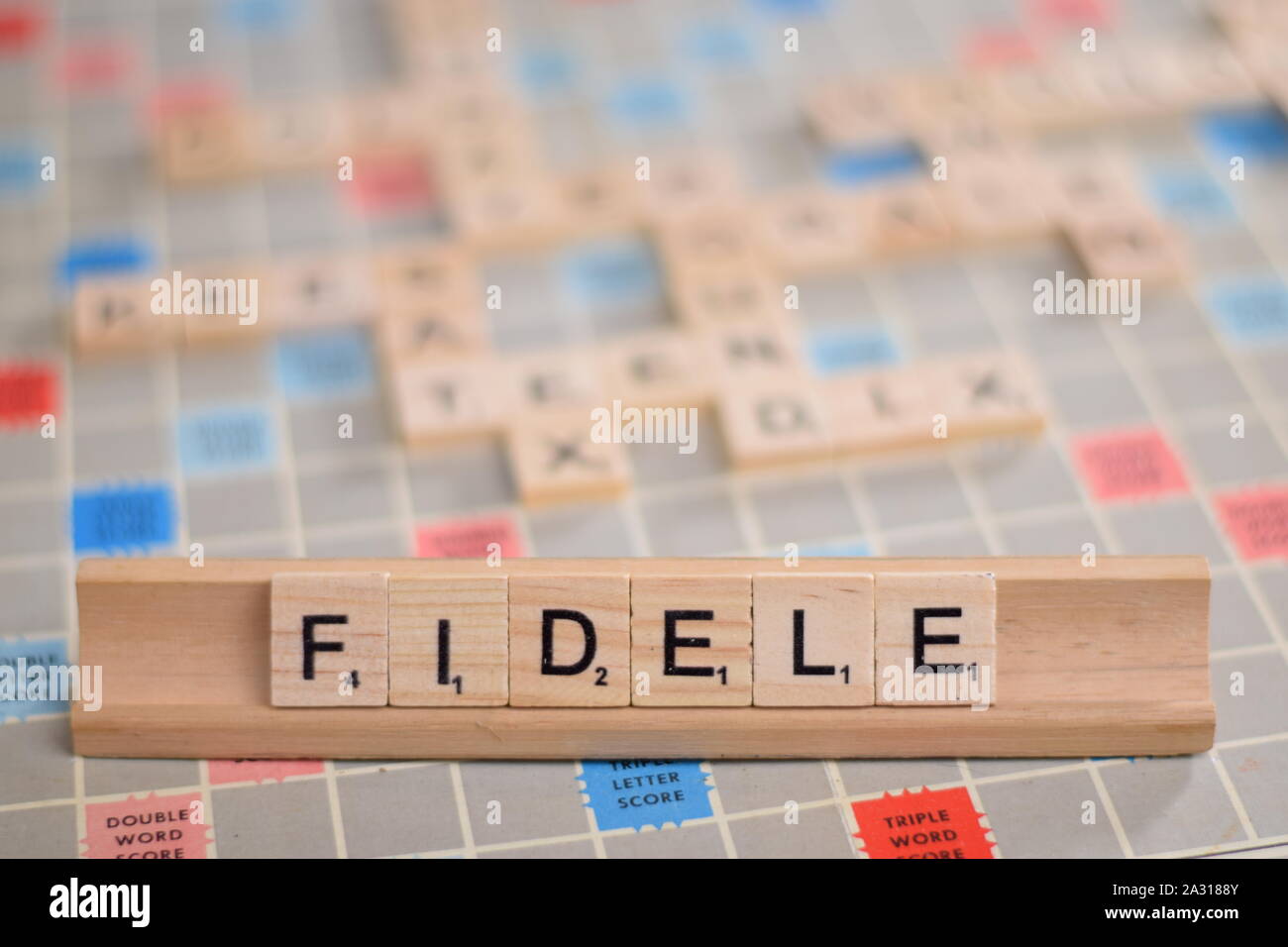 Le mot français "fidèle" (en anglais : 'fidèles') en tuiles de SCRABBLE en bois sur une grille. L'arrière-plan une carte vintage, des problèmes de mise au point, avec copie espace Banque D'Images