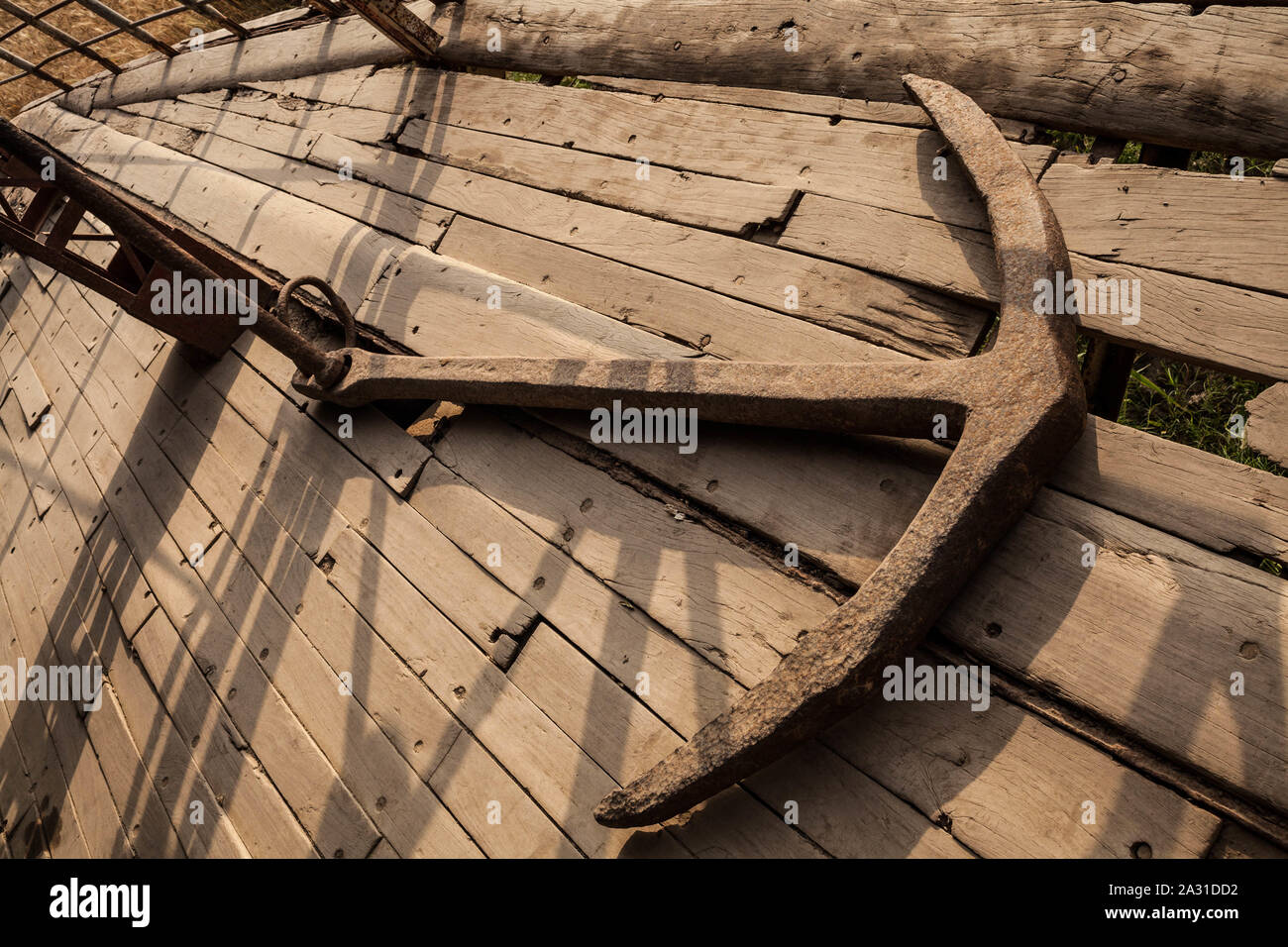 Une image évocatrice montrant une ancre rouillée imprégnée d'histoire maritime, reposant sur le plancher de bois vieilli d'un navire d'époque. Banque D'Images