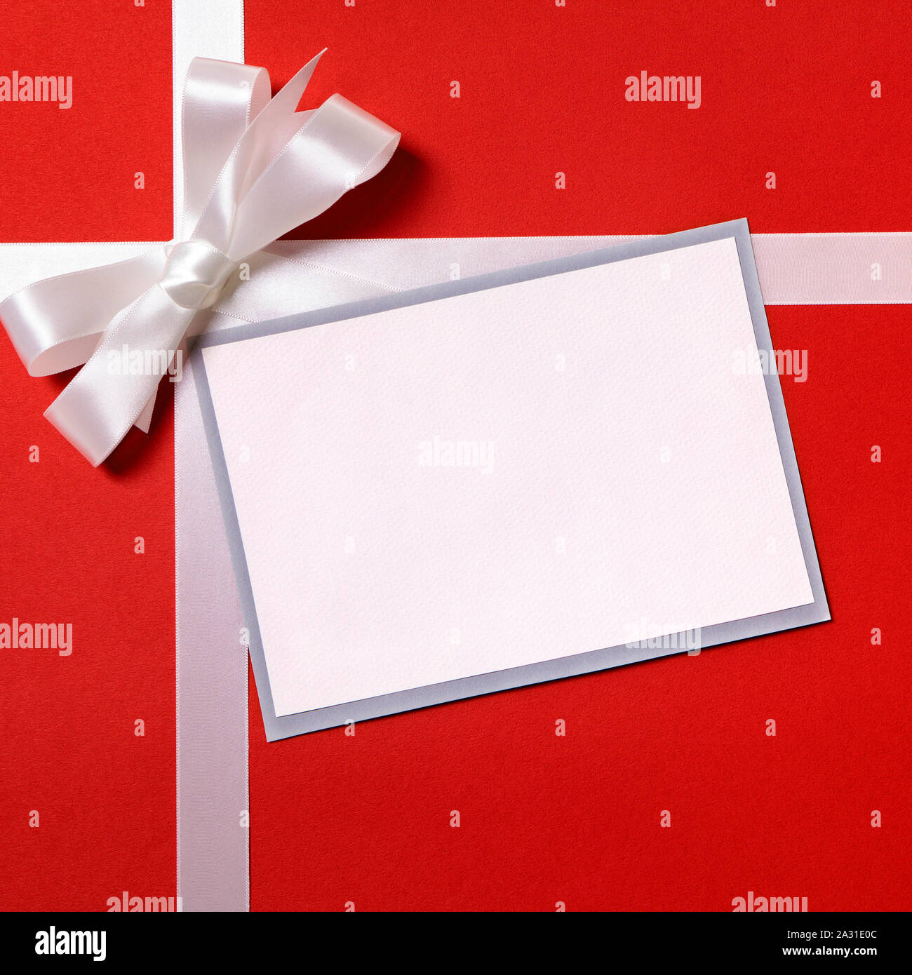 Carte-cadeau de Noël ou de l'étiquette et enveloppe, White Ribbon bow, rouge wrapping paper background, copy space Banque D'Images
