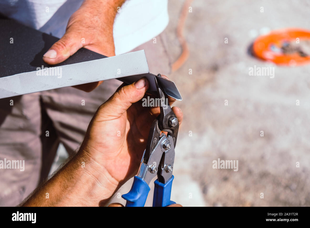 Worker cutting la tôle de solin avec mains ciseaux Banque D'Images