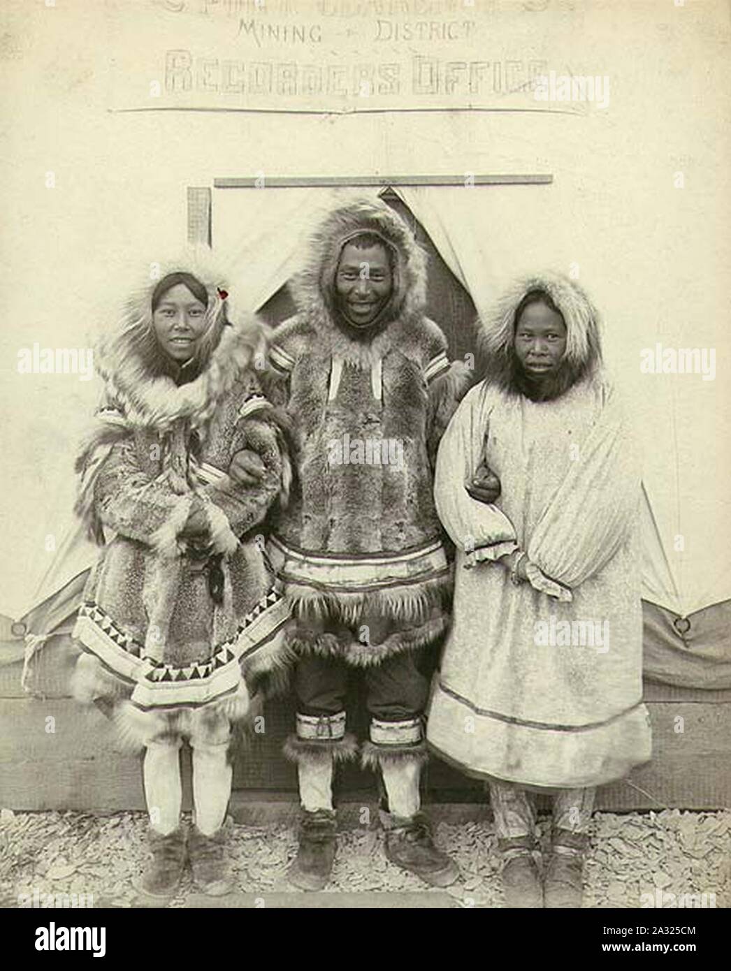 Eskimo homme et deux femmes debout devant le bureau de l'exploitation minière, de Port CLARENCE, Alaska, ca 1900 (HESTER 292). Banque D'Images