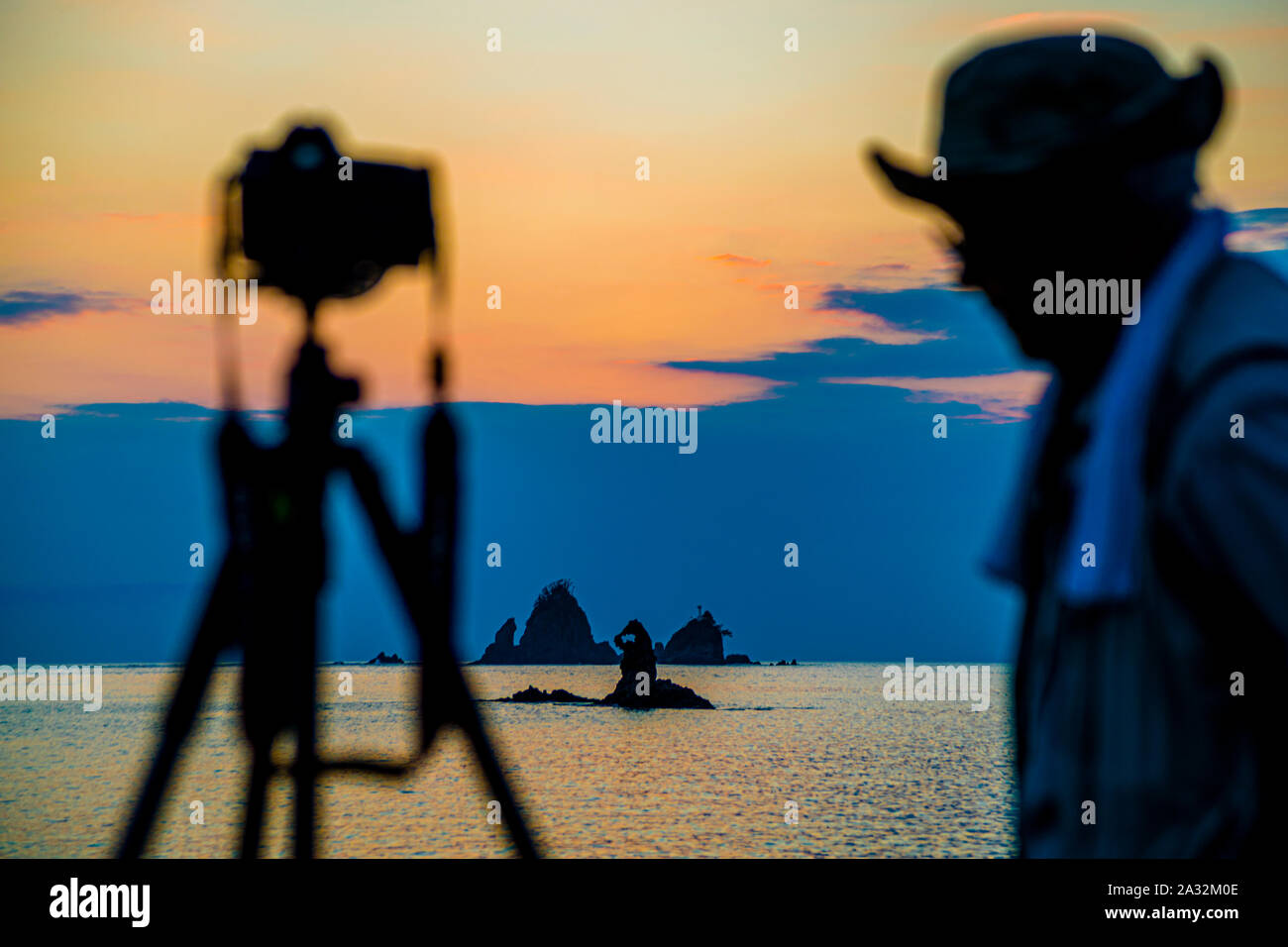 Sur la plage de la baie de Tago, d'innombrables photographes de coucher de soleil prennent leur position dans la soirée, attendant le moment où la boule du soleil glisse dans la gorge naturelle et ronde des rochers pour un court moment comme une pierre précieuse Banque D'Images