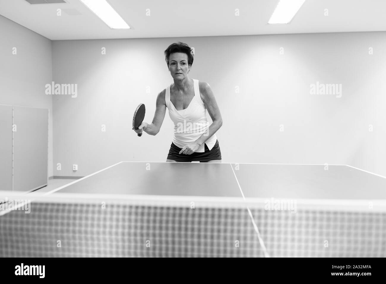 Belle femme mature à jouer au tennis de table à l'intérieur Banque D'Images Belle femme mature à jouer au tennis de table à l'intérieur Banque D'Images