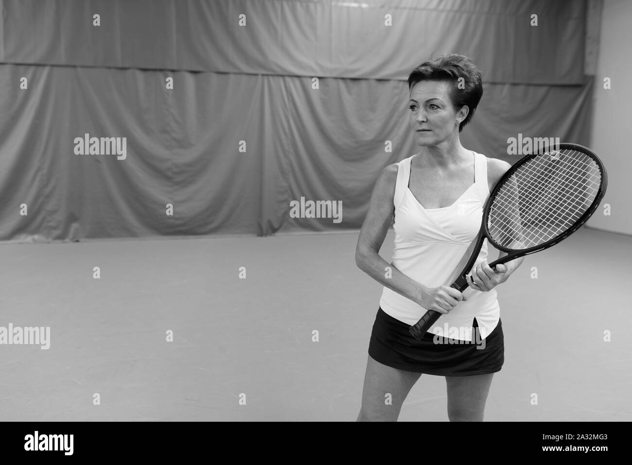 Belle femme mature jouer au tennis à cour intérieure Banque D'Images