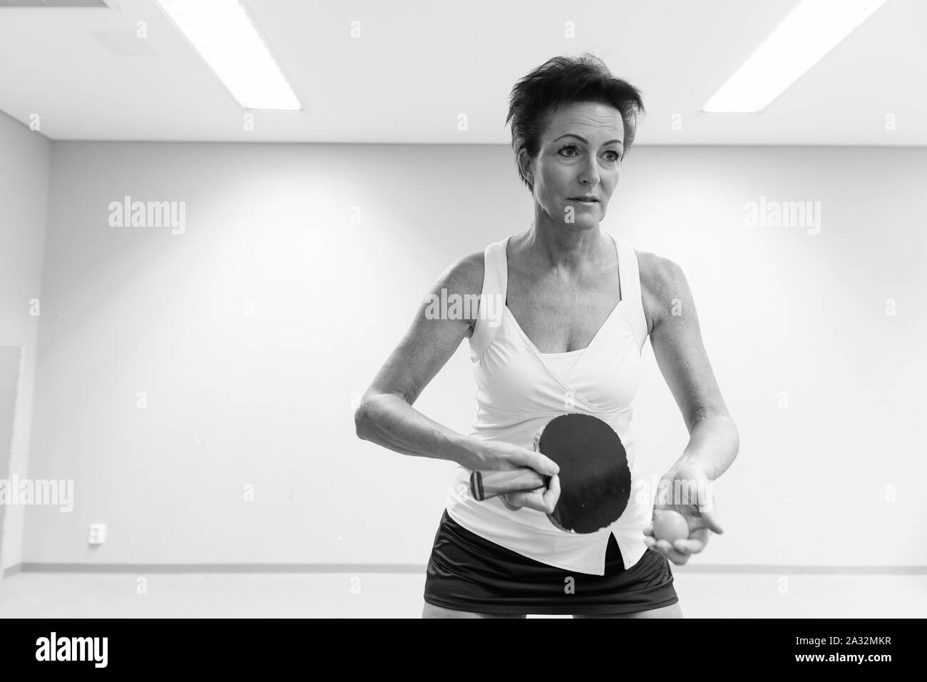 Belle femme mature à jouer au tennis de table à l'intérieur Banque D'Images Belle femme mature à jouer au tennis de table à l'intérieur Banque D'Images