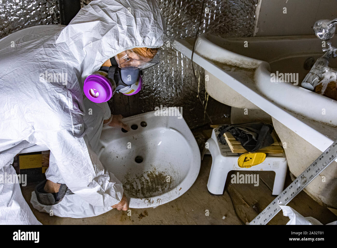 Un inspecteur de l'environnement est vu de près, avec des protections qu'il retire du bassin et d'une salle de bains privative condamné lors d'une évaluation à domicile. Banque D'Images