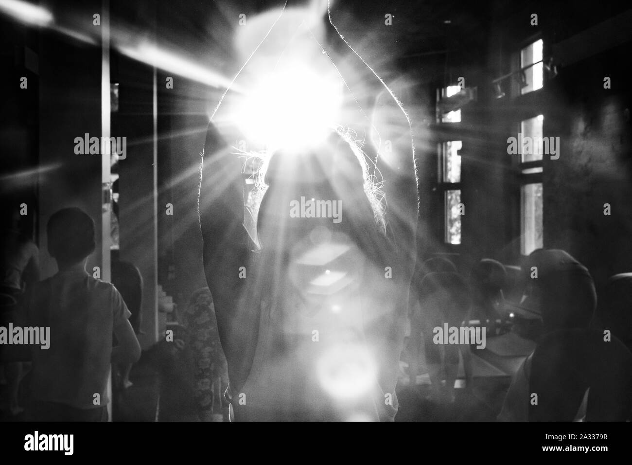 Un écran monochrome rétro-éclairé et d'une femme vue pratiquer 108 soleil salue dans une salle de sport, vus de derrière, alors qu'elle est confrontée à la vive lumière du soleil et rend hommage aux changement de saison. Banque D'Images