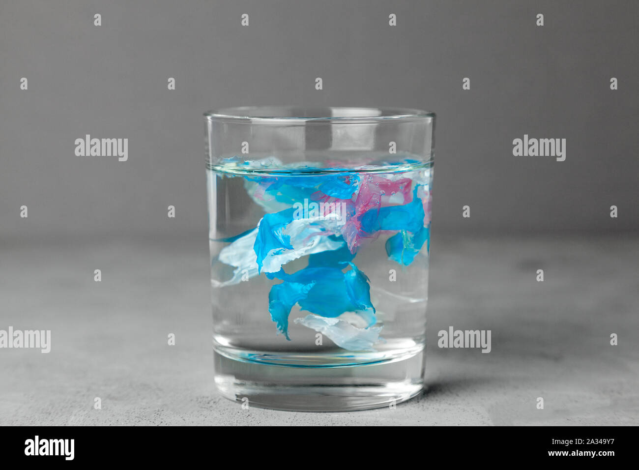 Microplastic. La pollution de l'eau par de petites particules de plastique. Verre d'eau avec du plastique. Banque D'Images