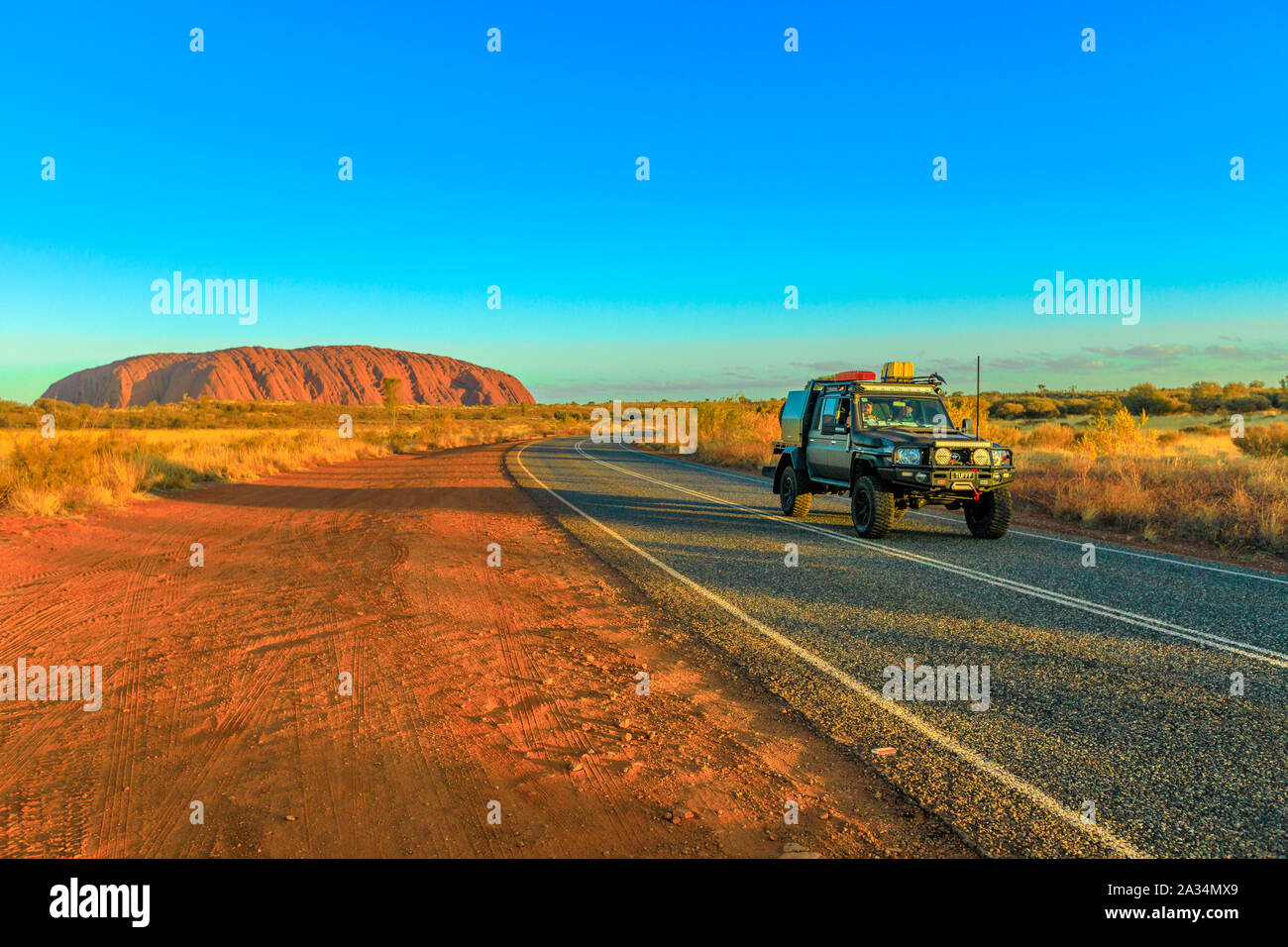 Uluru, dans le Territoire du Nord, Australie - Aug 25, 2019 : 4X4 véhicule sur la route menant à l'Uluru Ayers Rock dans le Parc National d'Uluru-Kata Tjuta au coucher du soleil Banque D'Images