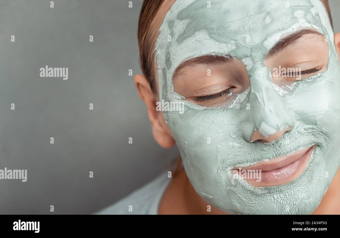 Closeup portrait d'une belle femme avec de l'argile bleue sur le visage, masque anti acné ou anti age soin de spa, la santé de la peau, fond gris Banque D'Images