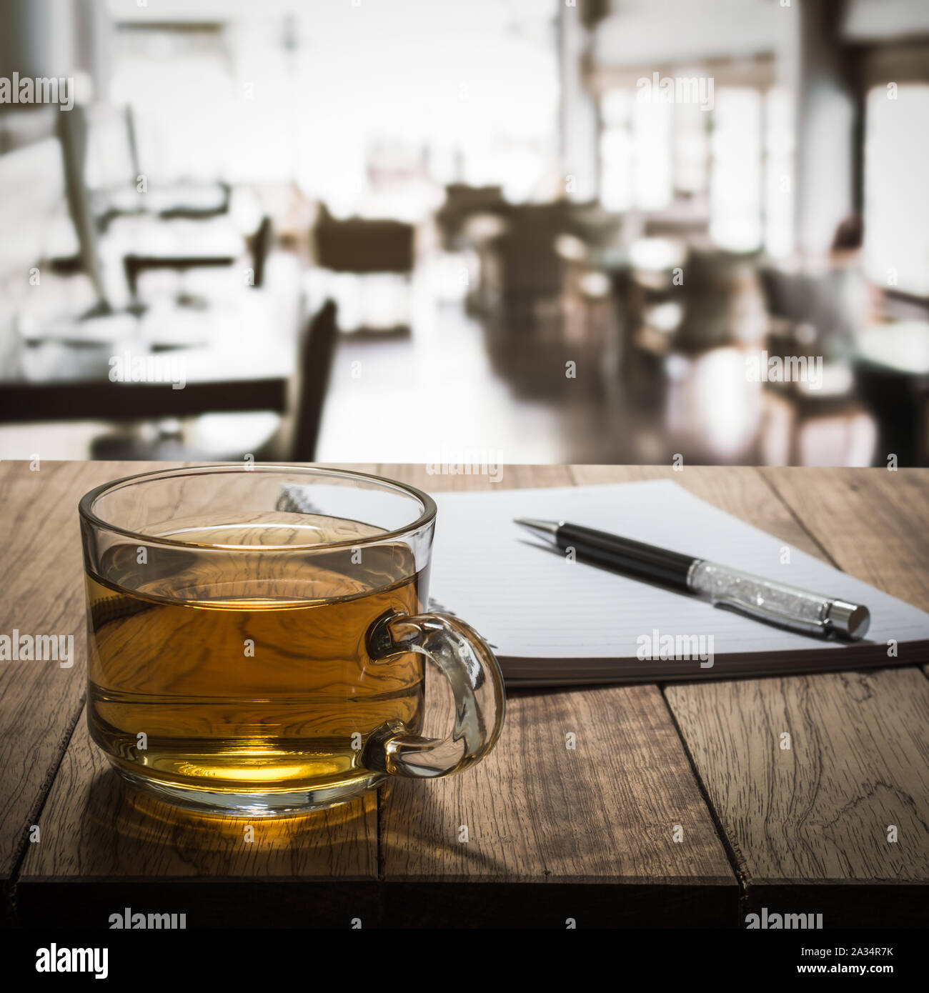 Le thé chaud avec carnet et un stylo sur la table en bois dans un café internet Banque D'Images