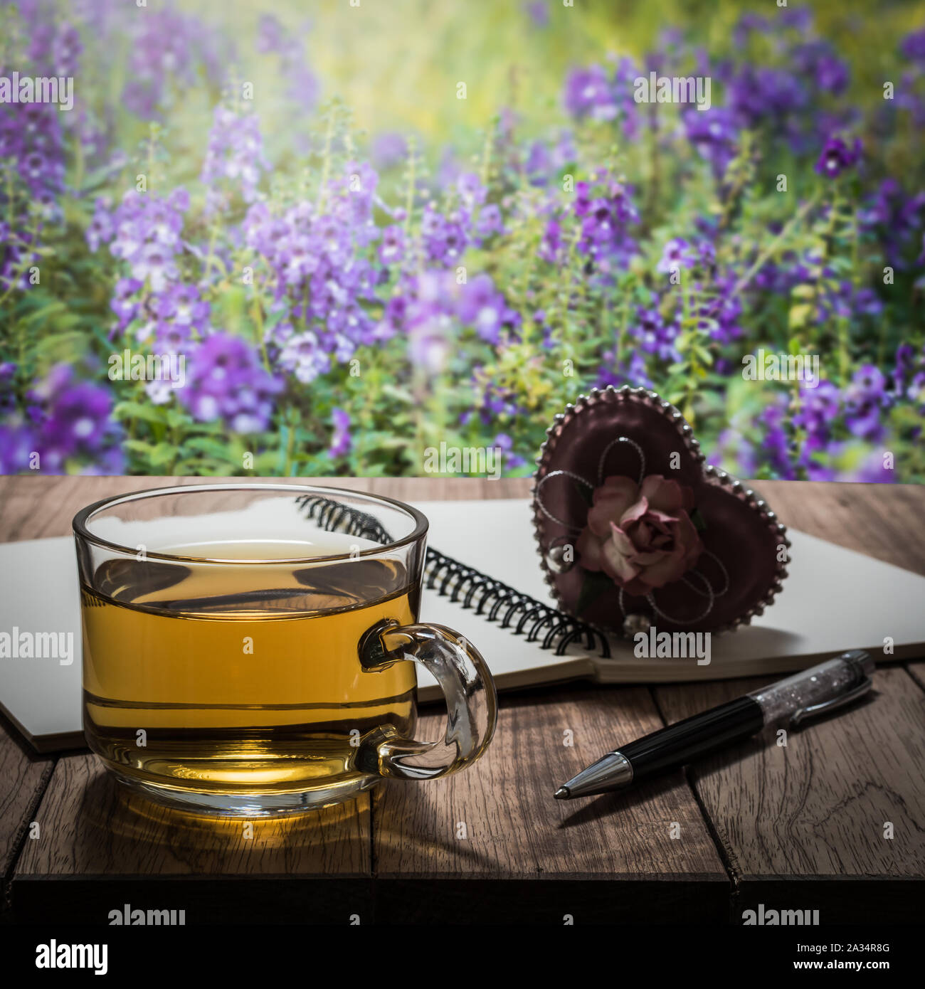 L'heure du thé avec coeur cadeau, carnet et un stylo sur la table en bois dans le jardin Banque D'Images