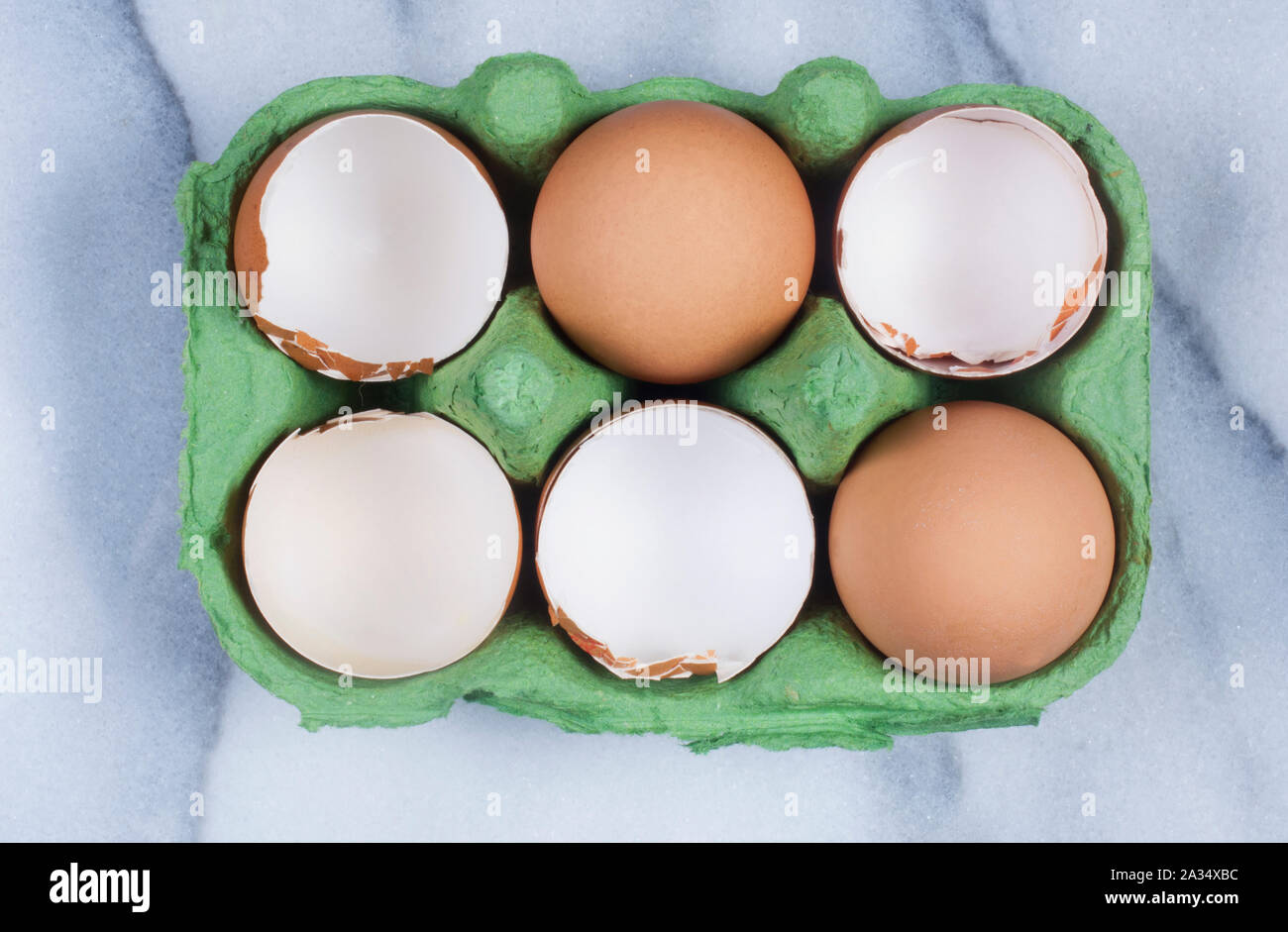 Studio shot de craquage, coquilles d'œufs de poulet vide dans une boîte sur un fond de marbre - John Gollop Banque D'Images