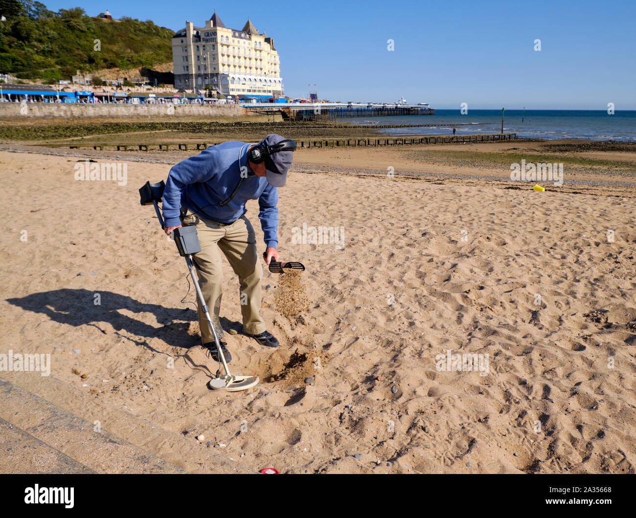 L'homme en habit d'automne à la plage avec un détecteur de métal à tamiser  le sable à la recherche des trésors sur la ville côtière sur Llandudo, au  Pays de Galles Photo