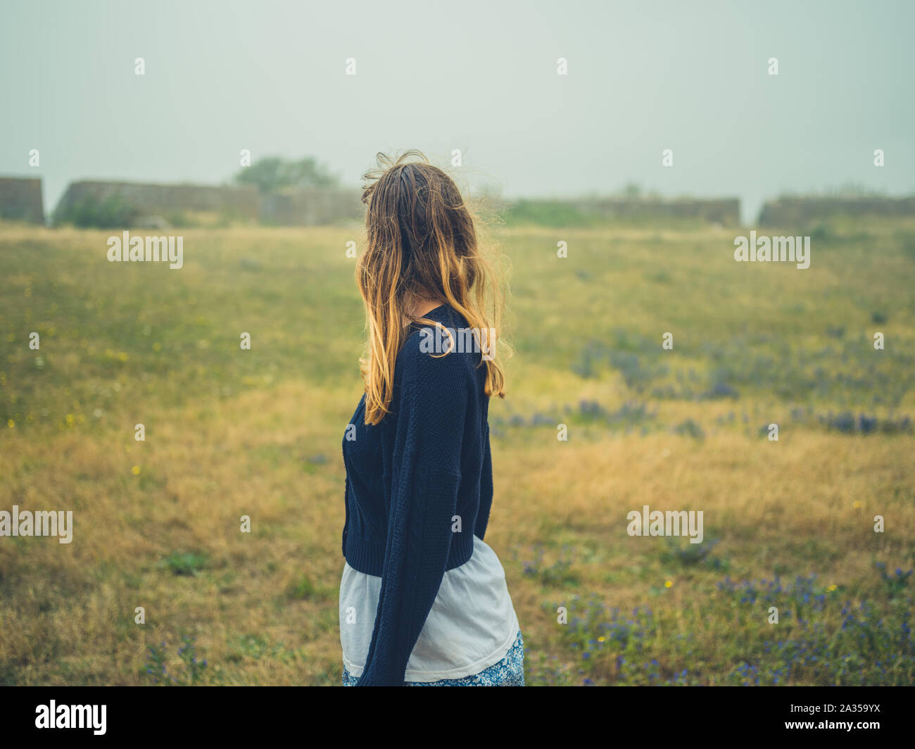 Une jeune femme se tient debout dans un champ de ruines historiques dans la brume Banque D'Images