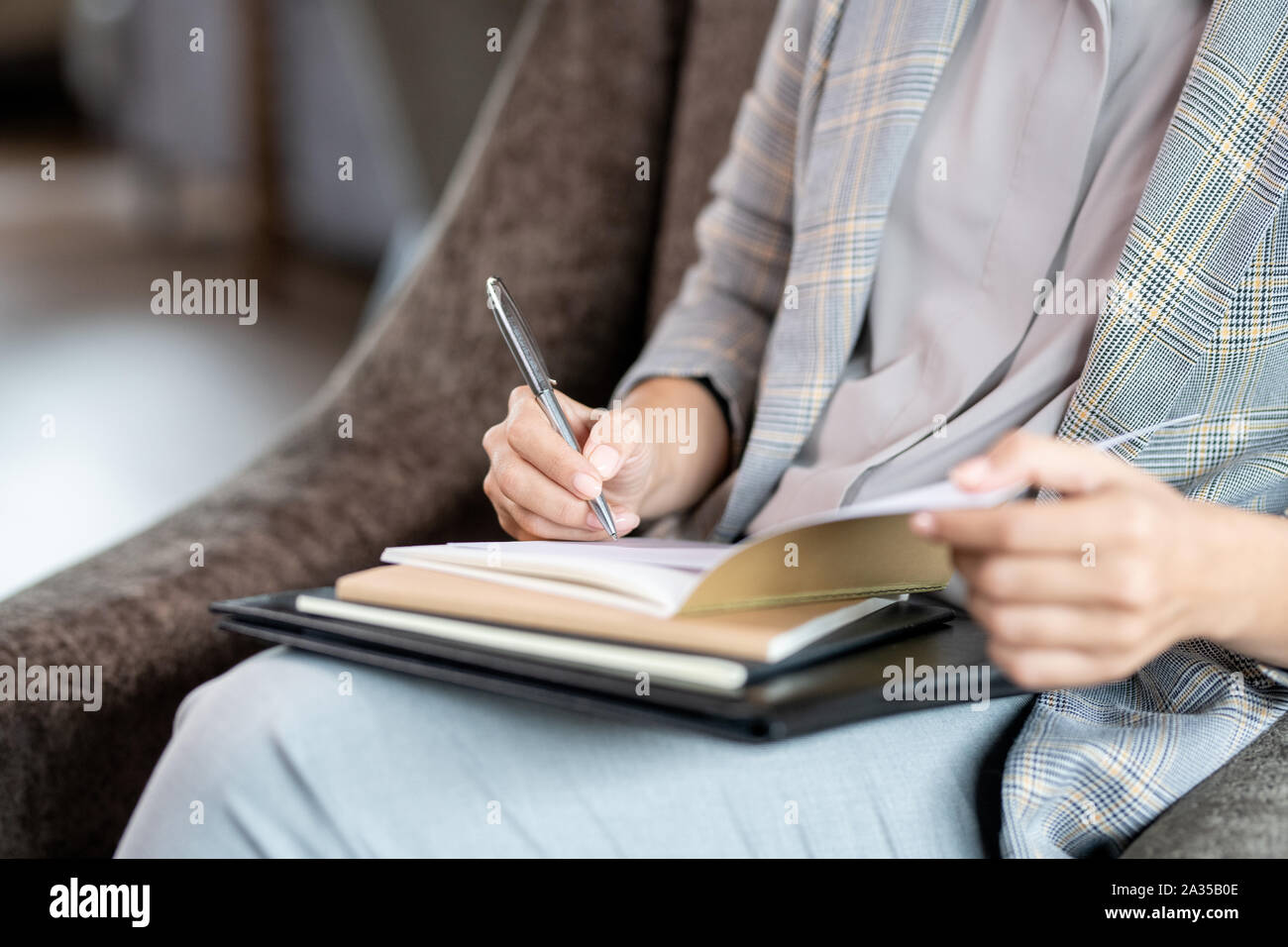 Mains de jeune femme élégante avec un crayon sur la page de cahier Banque D'Images