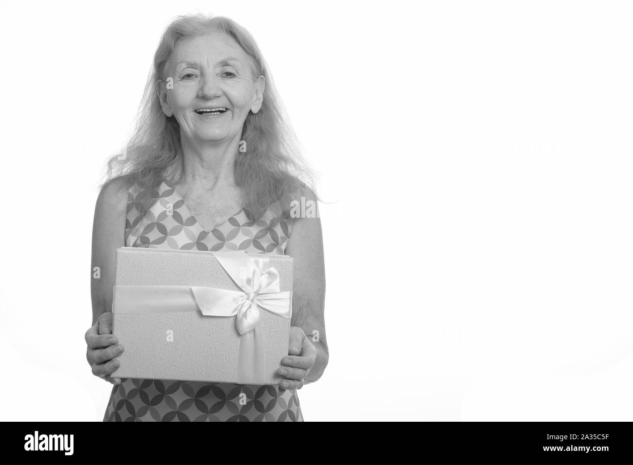 Studio shot of senior woman smiling and holding gift box Banque D'Images
