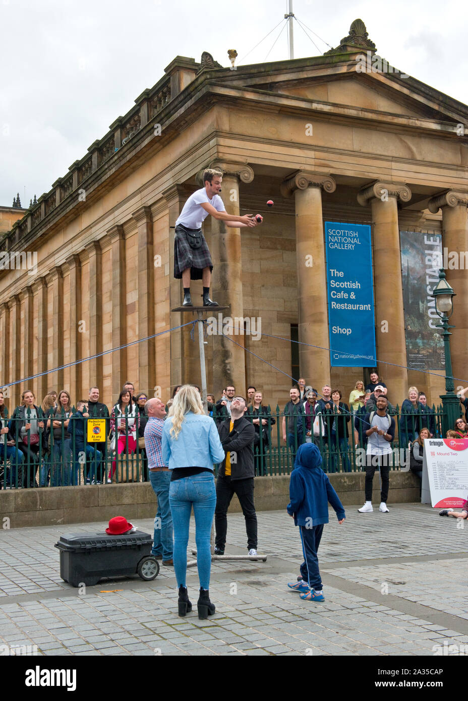 Artiste de rue et jongleur en équilibre sur poteau. En dehors de la Scottish National Gallery. Le monticule, Édimbourg. Banque D'Images