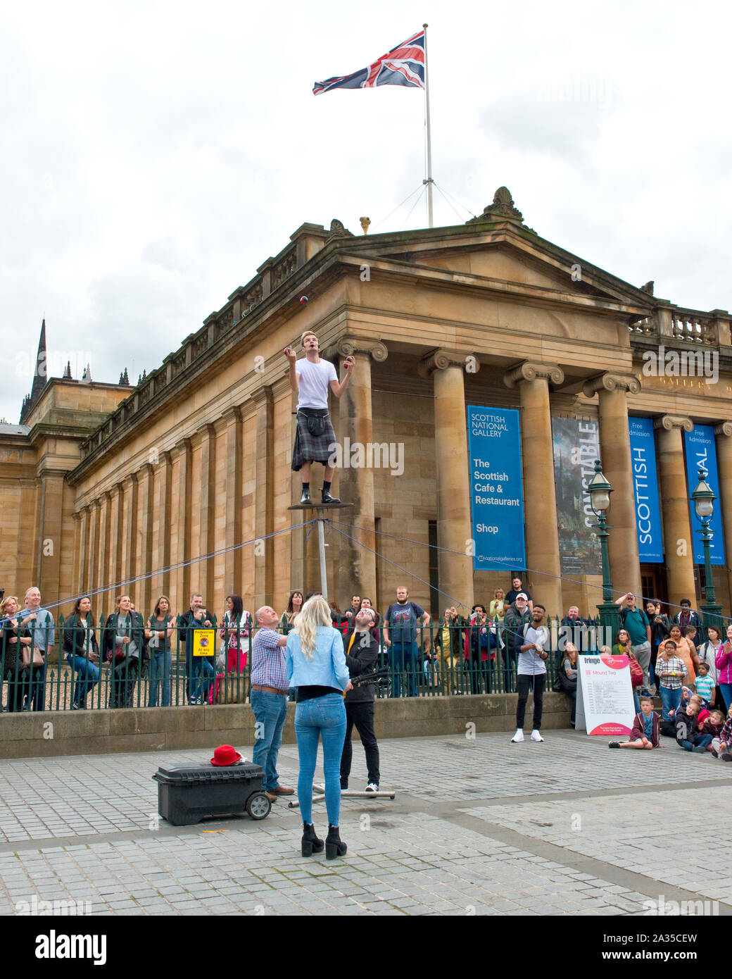 Artiste de rue et jongleur en équilibre sur poteau. En dehors de la Scottish National Gallery, Édimbourg. Banque D'Images