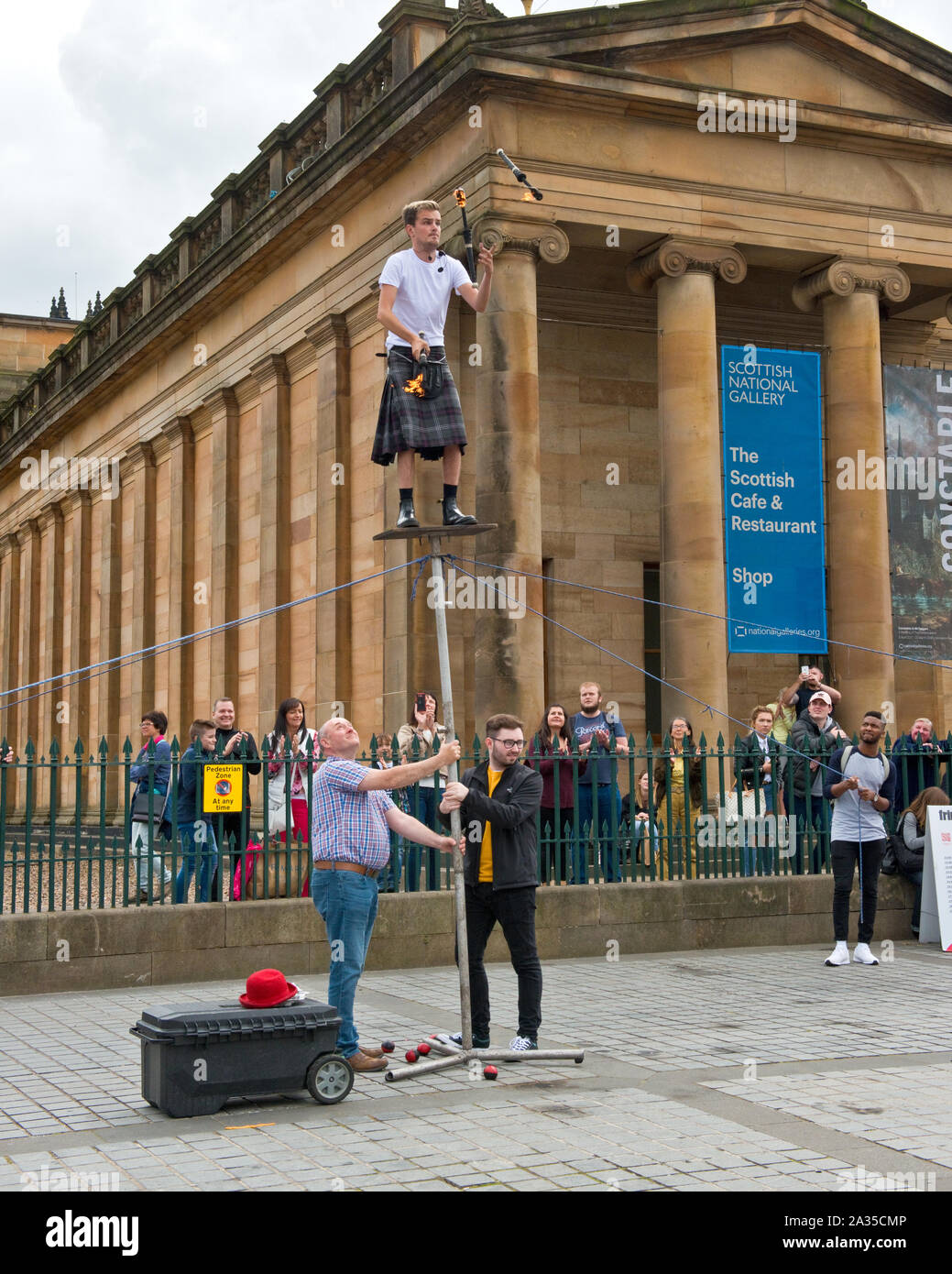 Artiste de rue et jongleur en équilibre sur poteau. En dehors de la Scottish National Gallery. Le monticule, Édimbourg. Banque D'Images