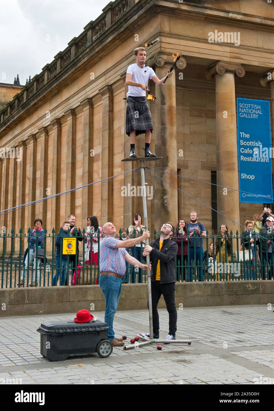 Artiste de rue et jongleur en équilibre sur poteau. En dehors de la Scottish National Gallery, Édimbourg. Banque D'Images