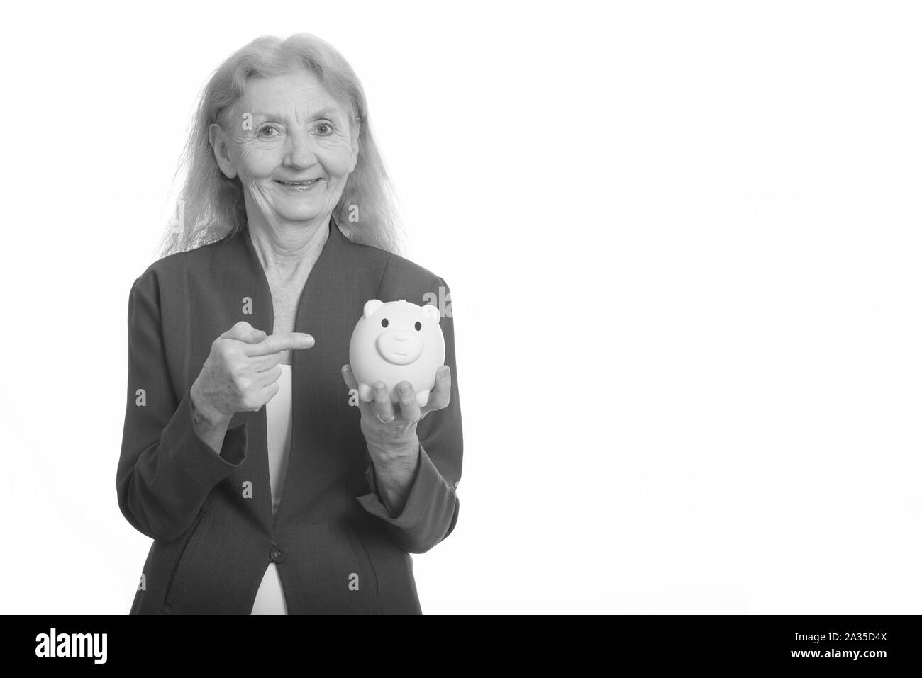 Happy businesswoman smiling while holding piggy bank et montre de l'index Banque D'Images