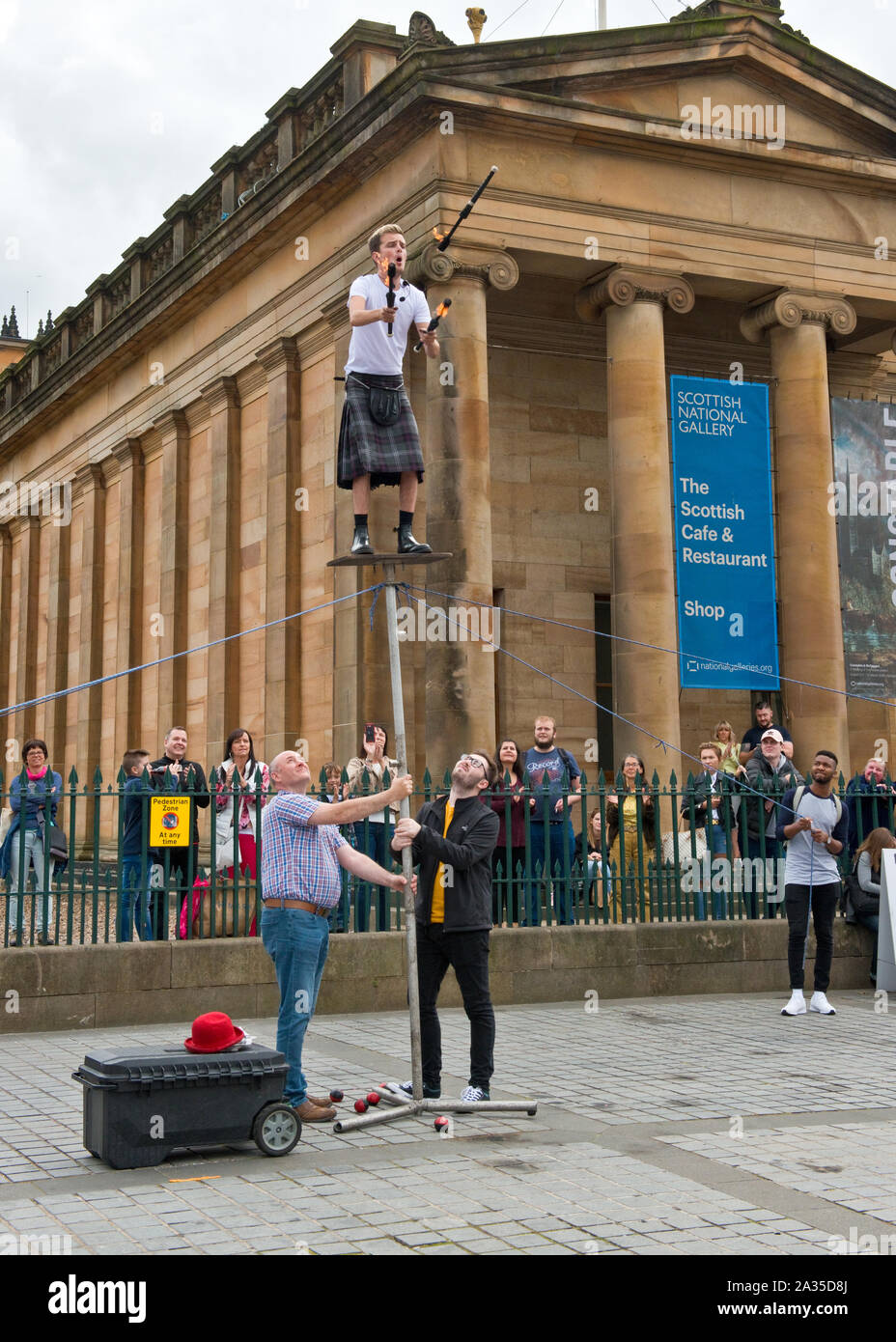 Artiste de rue et jongleur en équilibre sur poteau. En dehors de la Scottish National Gallery. Le monticule, Édimbourg. Banque D'Images