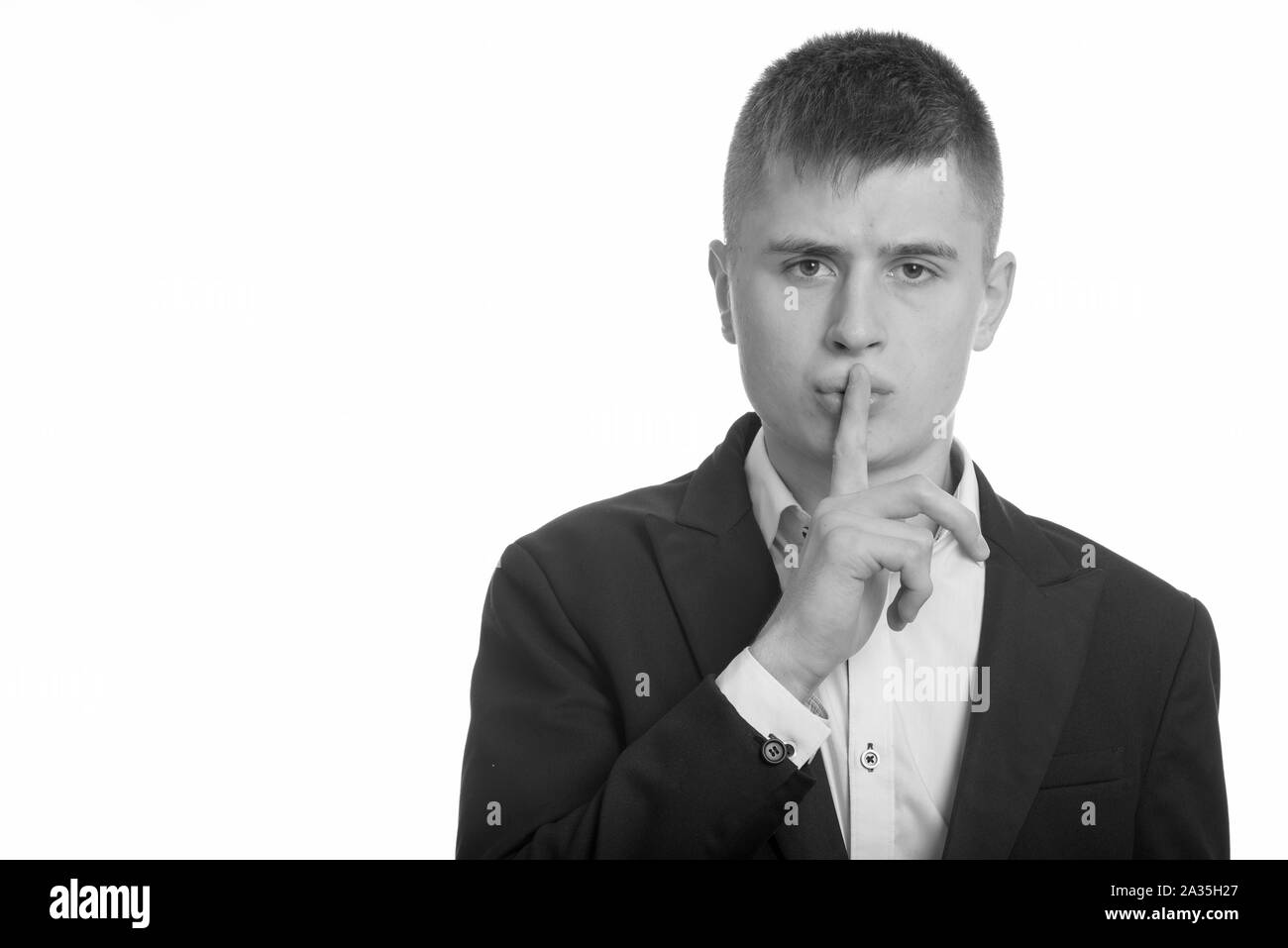 Studio shot of young businessman avec le doigt sur les lèvres Banque D'Images