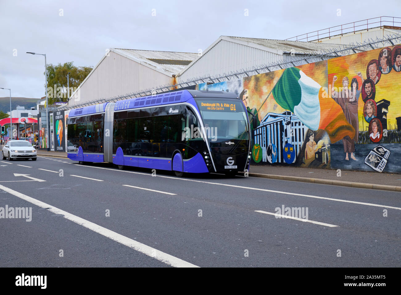 Transit planeur, Van Hool véhicule 18 ExquiCity à Belfast. Bus sur la rue de l'Ouest de Belfast en passant par le mur de la paix Banque D'Images