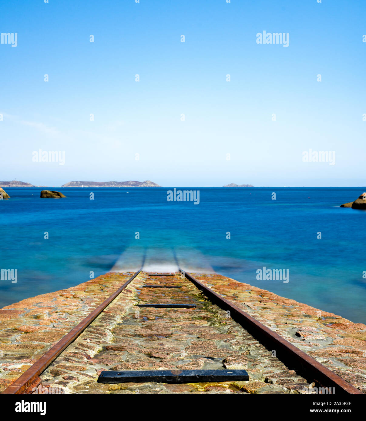 Format carré vue d'un ancien bateau de pierre rampe pour les bateaux de sauvetage menant dans un océan bleu calme sur la côte de Bretagne près de Perros-Guirec Banque D'Images