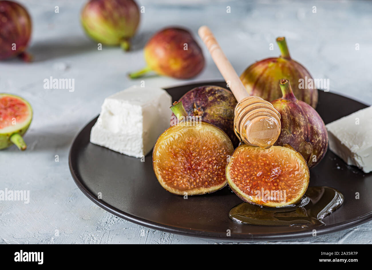 Fig, fromage feta et le miel sur la plaque noire sur surface grise, Close up Banque D'Images