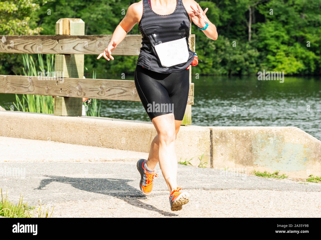 Une des femmes est l'exécution d'une course de 10K dans les bois, passage sur un pont tout en tournant autour d'un lac. Banque D'Images