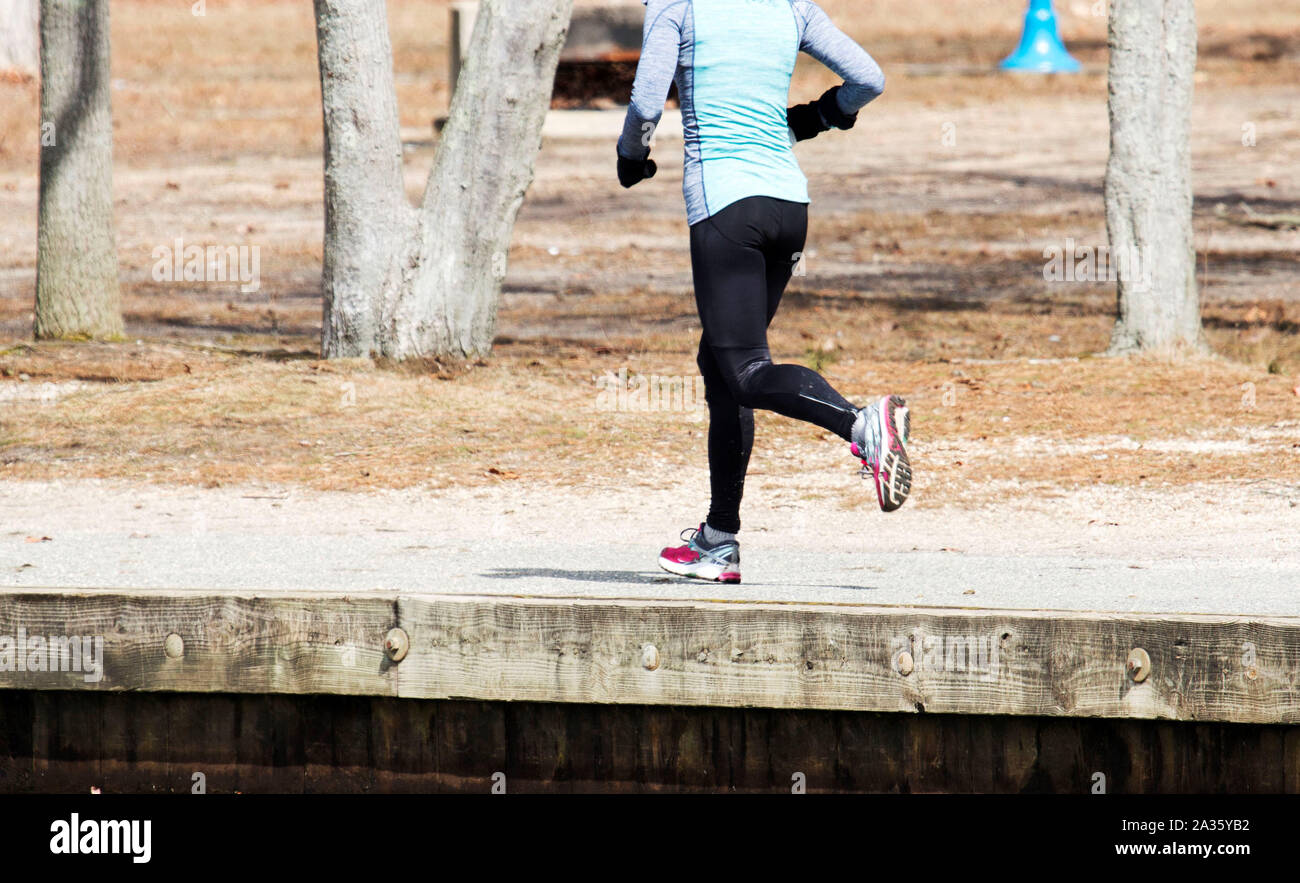 Une coureuse tourne autour d'un lac par une froide journée de Mars Banque D'Images