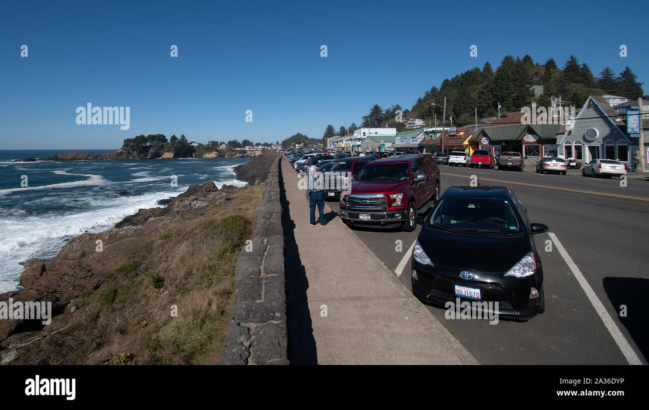 Depoe Bay, Oregon - 13 octobre 2019 : des voitures garées le long du littoral, avec des magasins de l'autre côté de la Route 101 l'autoroute. Banque D'Images